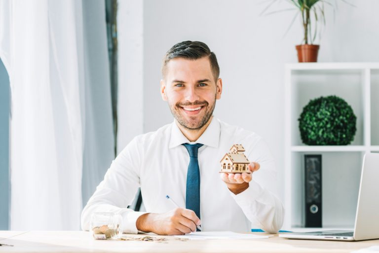 cheerful real estate agent showing toy house