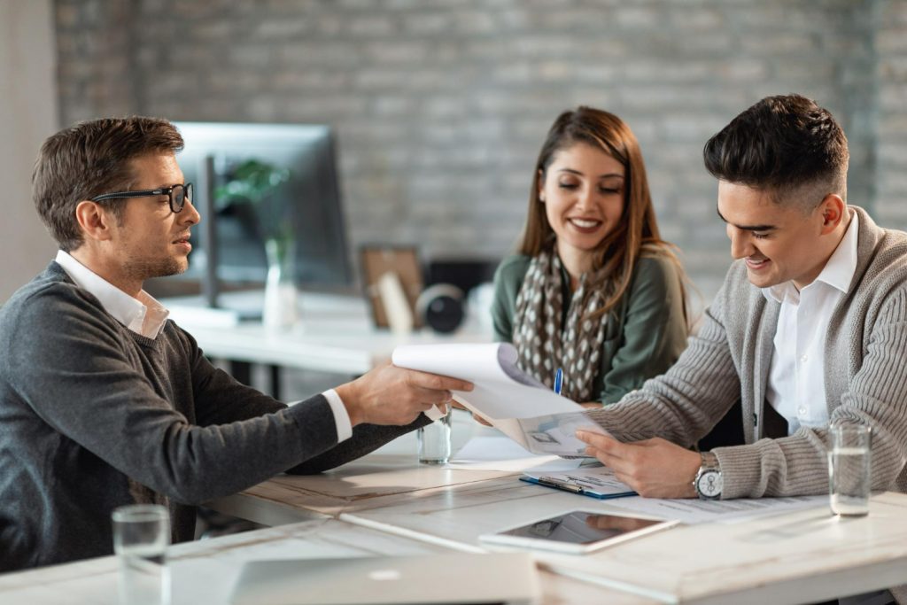 happy-couple-signing-contract-meeting-with-their-real-estate-agent-office